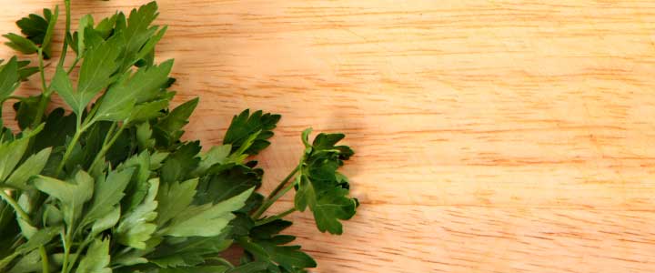 Es una planta aromática llamada perejil sobre una madera